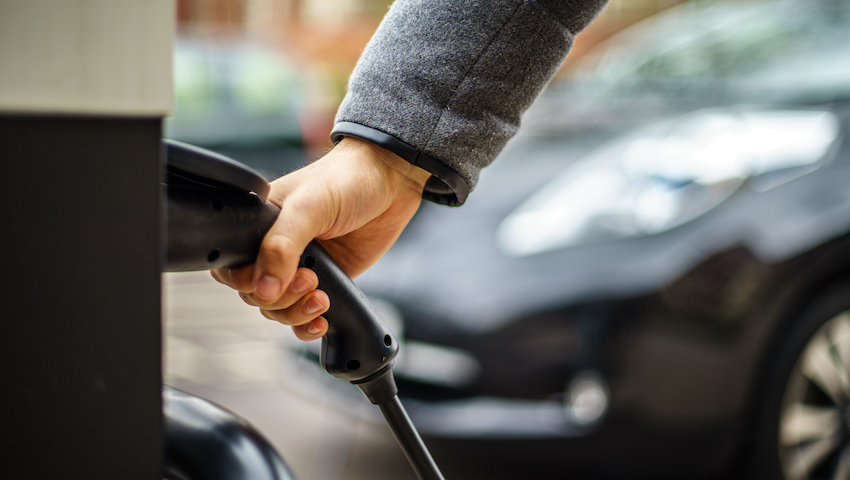 man plugging electric car into rapid charger uk