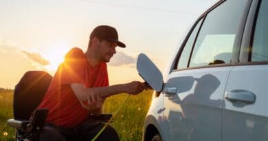 Man in wheelchair plugging in a charger in an electric car