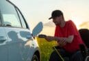 Man in wheelchair plugging in a charger in an electric car