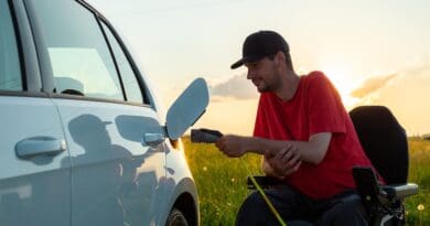 Man in wheelchair plugging in a charger in an electric car