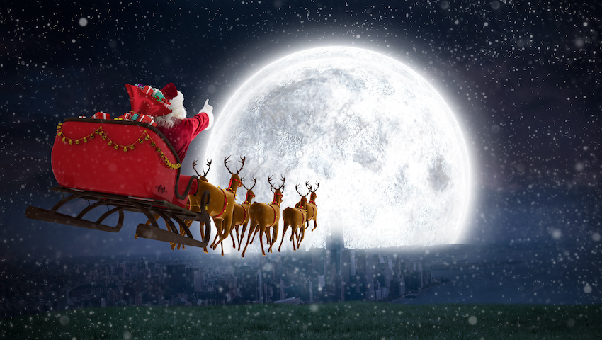 Santa Claus riding on sleigh with gift box against bright moon over city