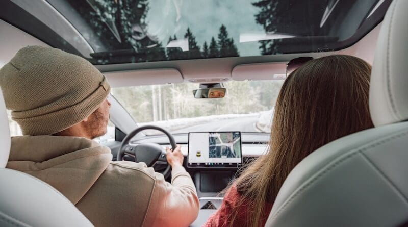 Couple driving in electric car go on a road trip.