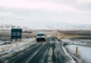 a car parked next to a sign with a snowy mountain in the background in Iceland