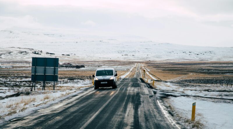 a car parked next to a sign with a snowy mountain in the background in Iceland