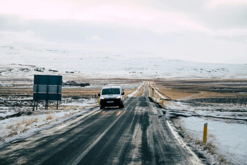 a car parked next to a sign with a snowy mountain in the background in Iceland